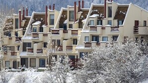 A row of multi-story buildings with balconies, set against a snowy landscape. - Storm Watch Condominiums by Pioneer Ridge Management (Steamboat Springs)