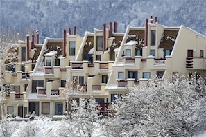 A row of multi-story buildings with balconies, set against a snowy landscape. - Storm Watch Condominiums by Pioneer Ridge Management (Steamboat Springs)