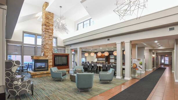 A spacious lobby with a fireplace, comfortable seating, a dining area, and a kitchen in the background. - Residence Inn by Marriott Cincinnati North/West Chester (West Chester)