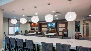 A conference room with a long table, chairs, a television, and a kitchen area. - Residence Inn by Marriott Cincinnati North/West Chester (West Chester)