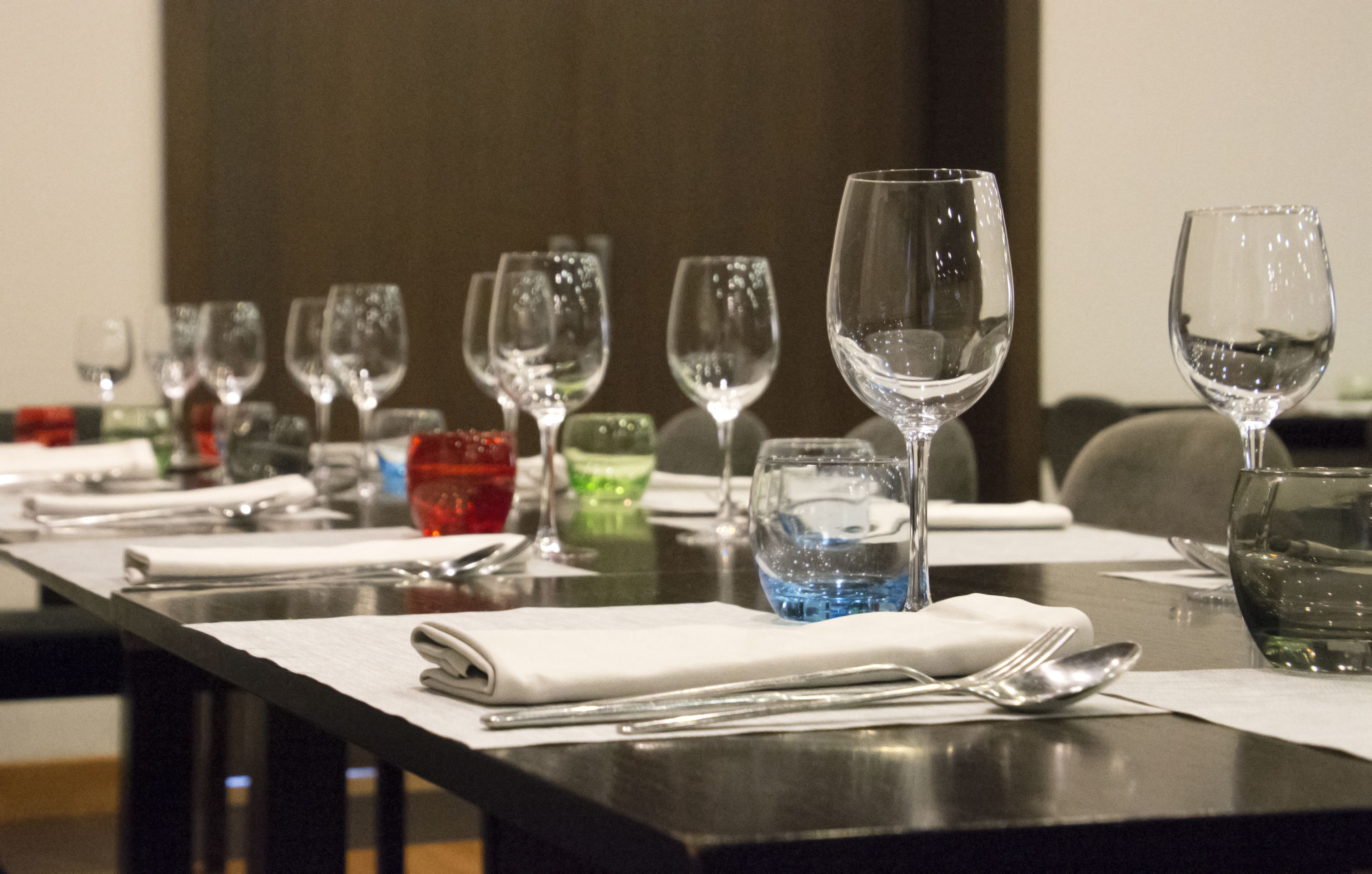 Una mesa de comedor dispuesta con varios vasos de vino, vasos de agua y cubiertos.