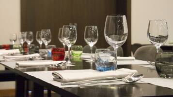 Una mesa de comedor dispuesta con varios vasos de vino, vasos de agua y cubiertos.