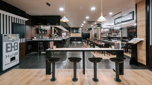A modern bar area with a long counter, stools, and overhead lighting. - Zenit Aparthotel Hall88 (Salamanca)