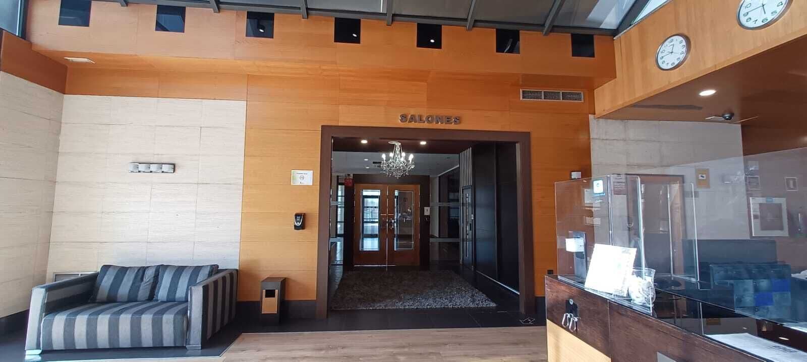 Un área de recepción con un sofá, un mostrador y un letrero que dice "SALONES".