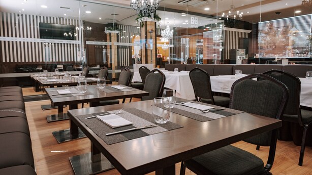 Un restaurante moderno con varias mesas, sillas y un candelabro.