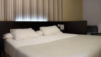 A hotel room with a large bed, a headboard, a nightstand, and a wall-mounted telephone.