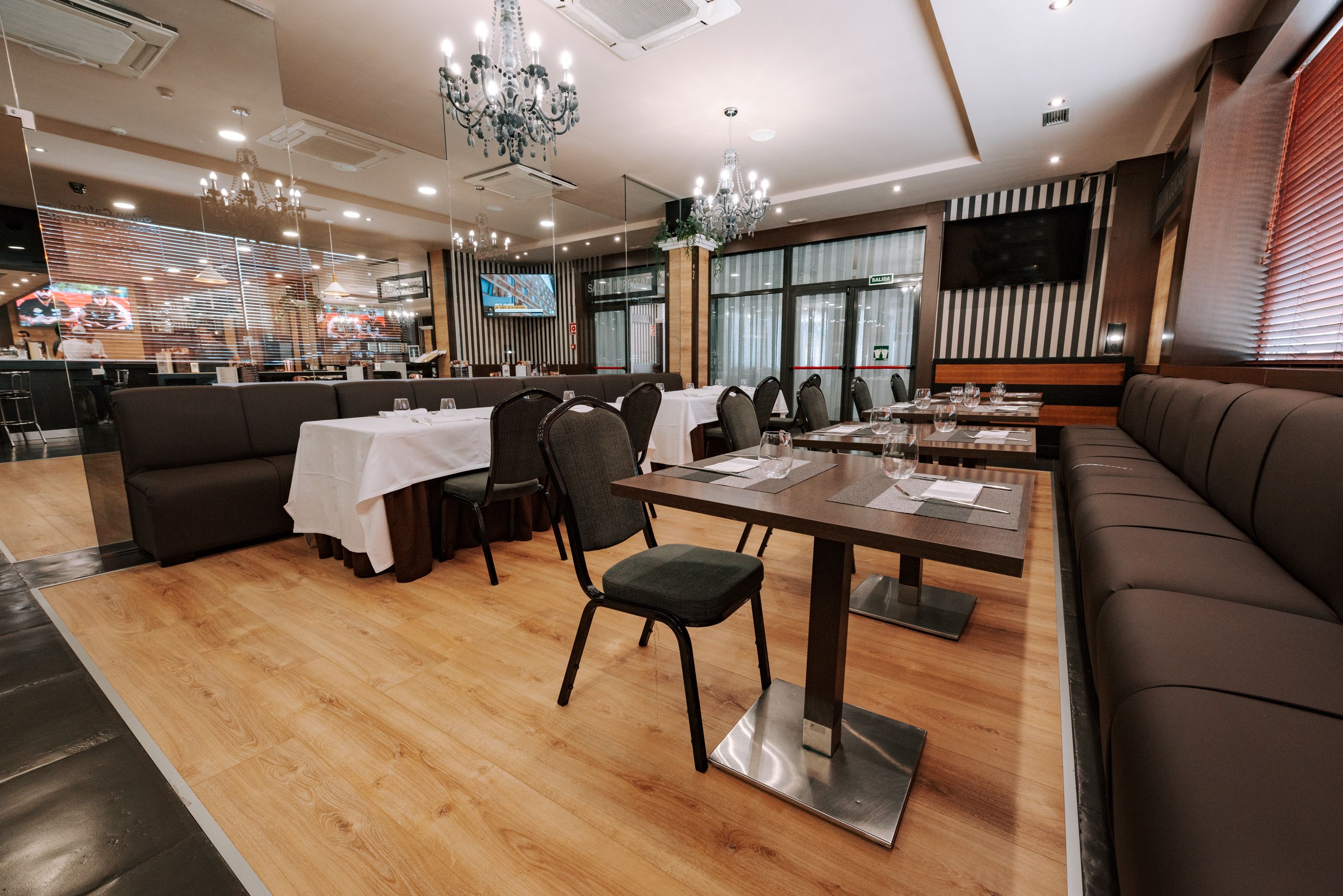 Un restaurante moderno con suelo de madera, un área de comedor central con mesas y sillas, y una pantalla grande que muestra un mapa.