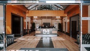 A hotel reception area with a modern design, featuring a reception desk, seating area, and a staircase leading to an upper level. - Zenit Aparthotel Hall88 (Salamanca)