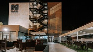 Un área de estar al aire libre con mesas y sillas, una escalera, y un edificio con un letrero que dice "Hall88 APARTMENT HOTEL".