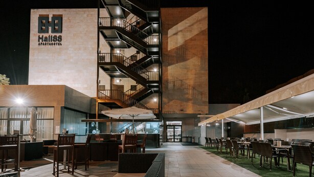 An outdoor seating area with tables and chairs, a staircase, and a building with a sign reading "Hall88 APARTMENT HOTEL". - Zenit Aparthotel Hall88 (Salamanca)