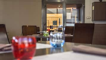 A modern dining area with a glass partition, a red and blue glass on the table, and a sign reading "SALONES" in the background.