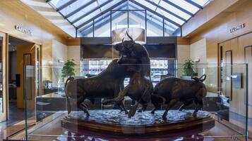 A glass display case with a bull statue in a modern building with wooden walls and a skylight.