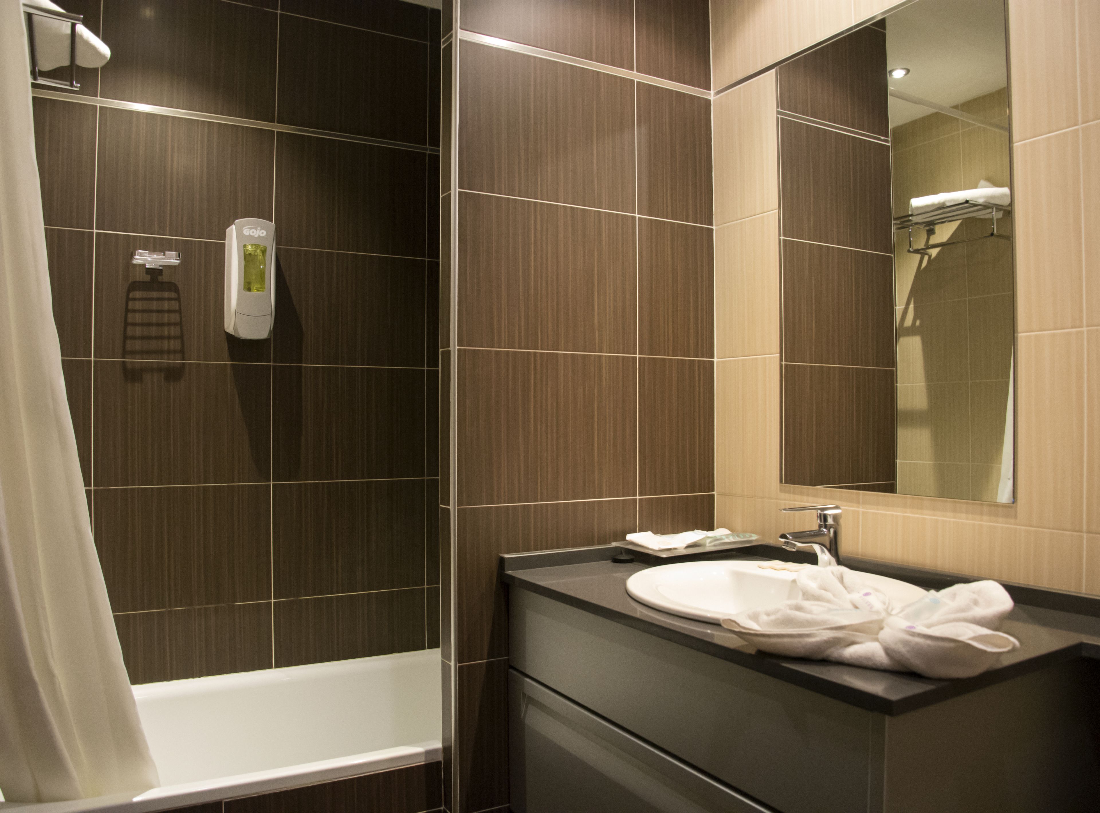 A modern bathroom with a bathtub, a sink with a mirror, and a towel rack.