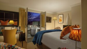 A hotel room with a bed, a desk, a chair, a TV, and a view of the outside. - Rocpool Reserve (Inverness)