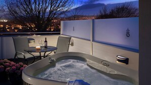 A hot tub with a towel, a table with chairs, and a candle. - Rocpool Reserve (Inverness)