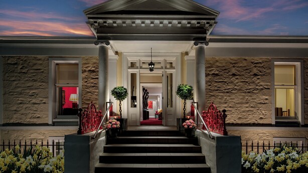A building with a grand entrance, steps leading up to a covered area, and a stone facade. - Rocpool Reserve (Inverness)