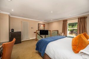 A hotel room with a bed, a desk, a television, and a view of the outdoors.