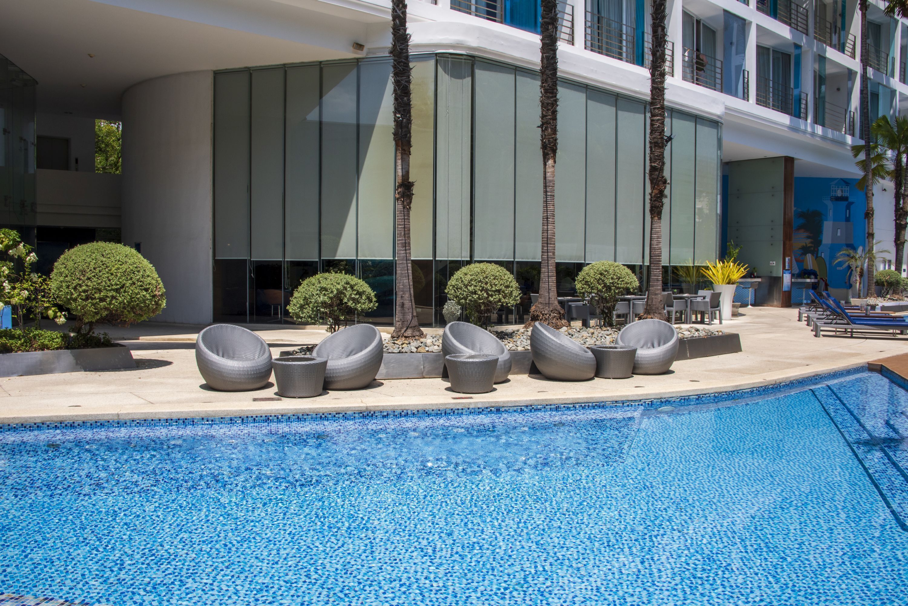 A modern hotel with a pool area, including lounge chairs and a clear blue pool.