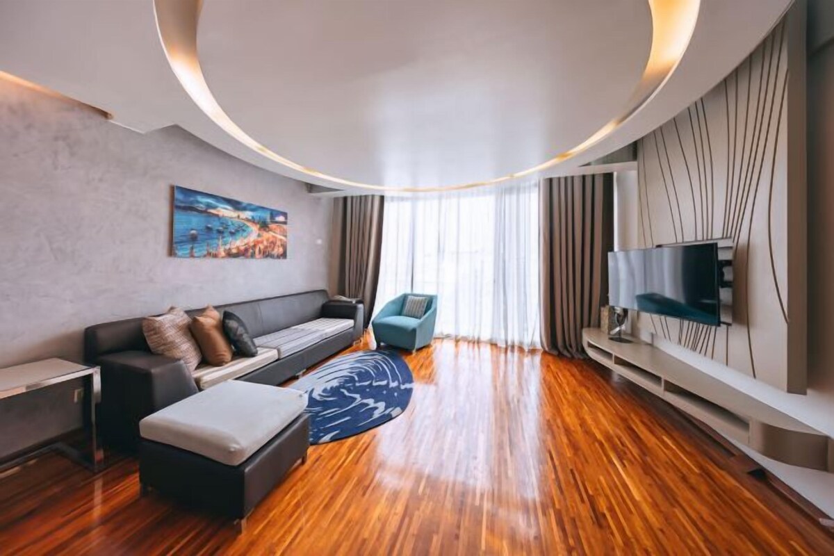 Una sala de estar moderna con piso de madera, un sofá, un televisor y un cuadro en la pared.
