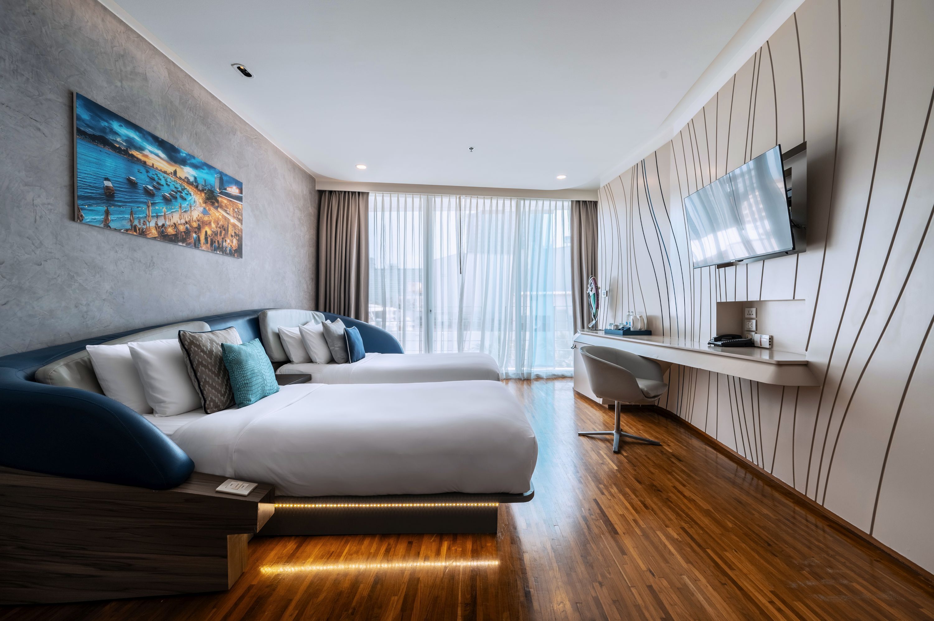 A modern hotel room with a large bed, a desk, and a TV mounted on the wall.