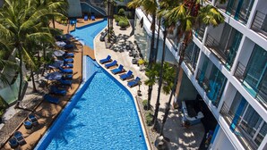 A swimming pool with lounge chairs and umbrellas, surrounded by palm trees and a modern building. - Hotel Baraquda Pattaya By Heeton  (Pattaya)