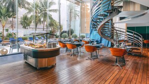 A modern indoor space with a central bar area, multiple seating arrangements, and a spiral staircase. - Hotel Baraquda Pattaya By Heeton  (Pattaya)