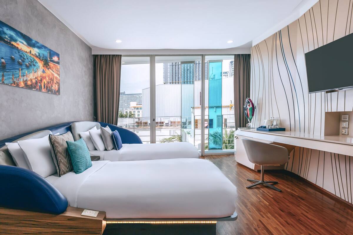 Una habitación de hotel moderna con una cama grande, un escritorio y un televisor.