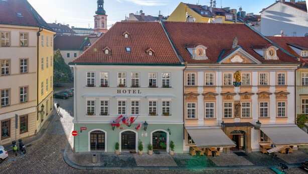 A historic hotel with a classic facade, a prominent entrance, and a clock tower in the background. - Betlem Club Hotel (Prague)