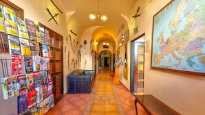 A hallway with a map, a bulletin board with magazines, and a bench. - Betlem Club Hotel (Prague)