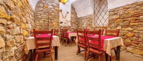 Un restaurant aux murs de pierre et aux tables et chaises en bois.
