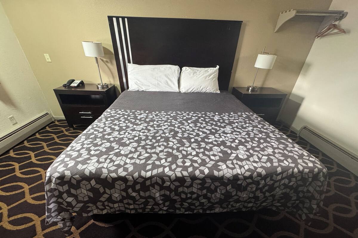 A hotel room with a bed, two bedside tables, a telephone, and a lamp.