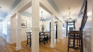A spacious hallway with wooden flooring and white columns, leading to a dining area with a chandelier. - BytheSea Inn  (Half Moon Bay)