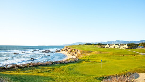 A coastal golf course with a clubhouse, ocean view, and rolling hills in the background. - BytheSea Inn  (Half Moon Bay)