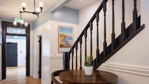 A staircase with black balusters, a round wooden table with a potted plant, and a poster on the wall. - BytheSea Inn  (Half Moon Bay)