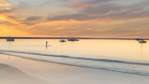 A calm beach with boats and a person walking along the shore. - BytheSea Inn  (Half Moon Bay)