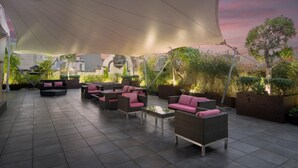 An outdoor patio area with seating arrangements and a large canopy providing shade.