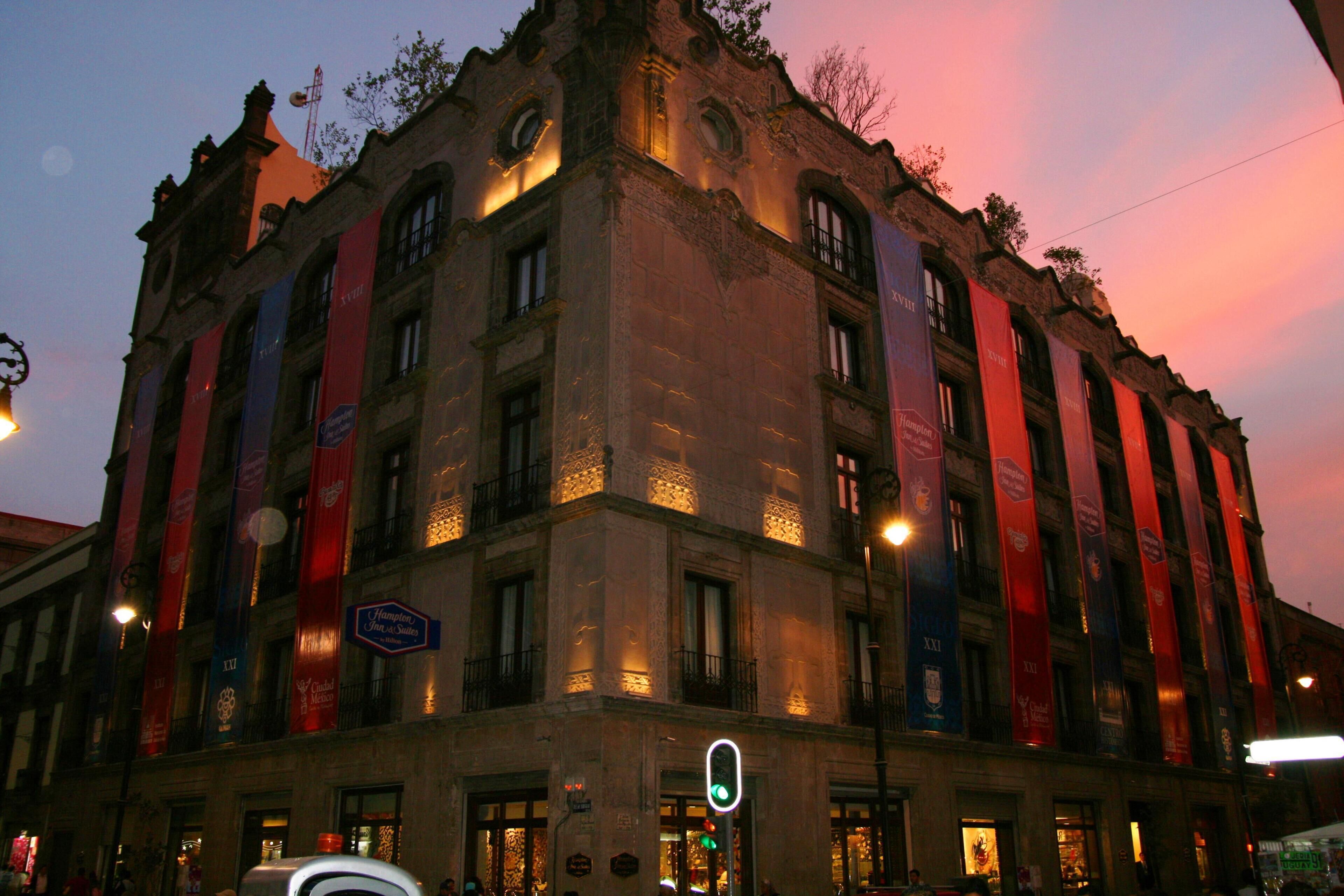 A historic building with multiple stories, large windows, and banners.