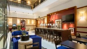A hotel lobby with a bar area, seating, and a staircase.