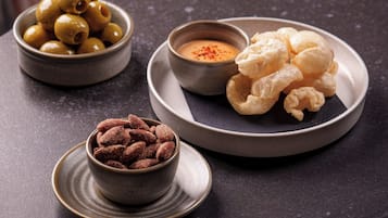 A table with three bowls containing olives, a creamy sauce, and a plate with pastries.