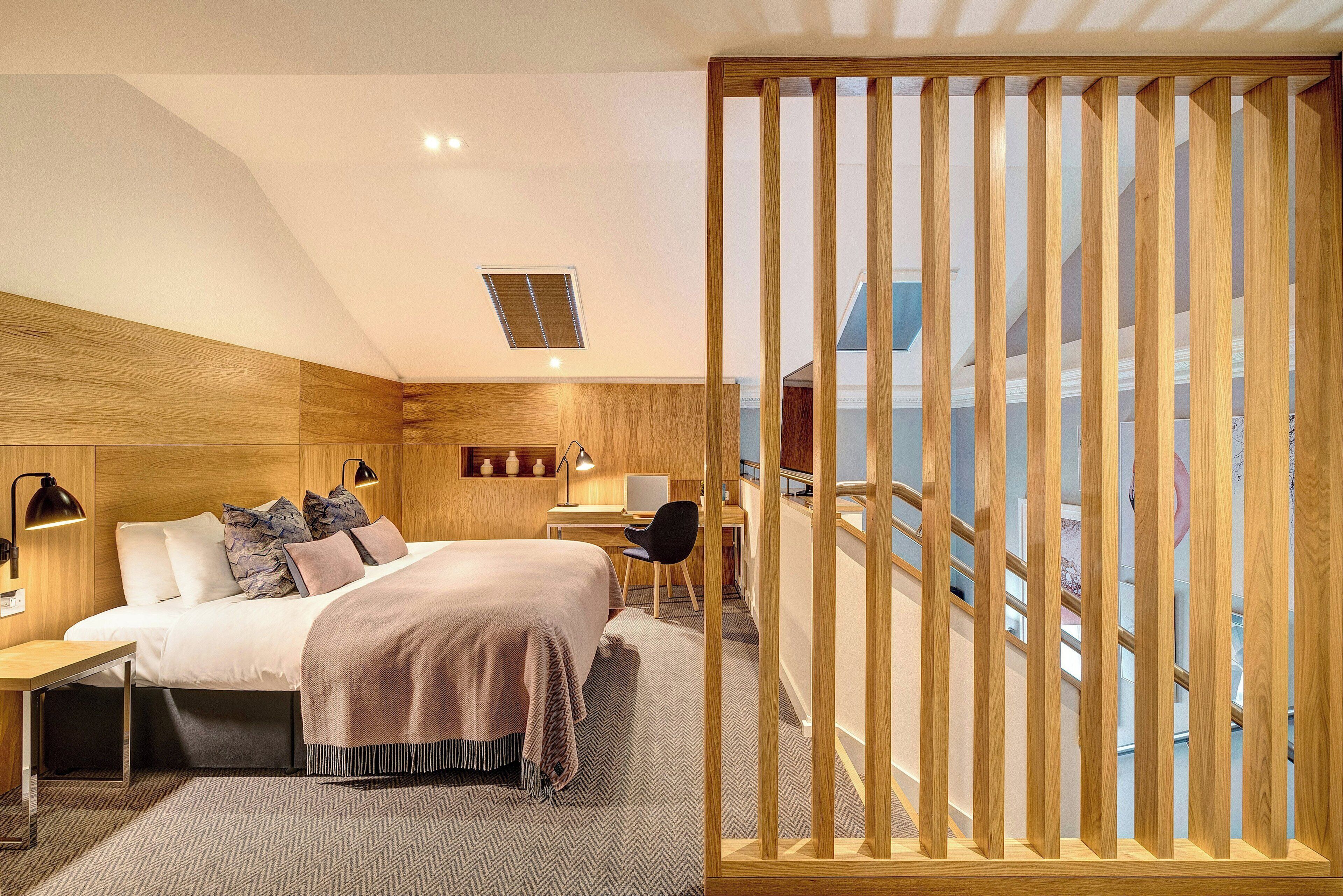 Quarto de hotel moderno com cama, escrivaninha, cadeira e vista para o exterior.