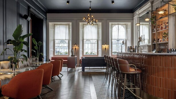A bar area with a herringbone floor pattern, bar stools, and a bar counter with a wooden finish. - Apex Waterloo Place Hotel (Edinburgh)