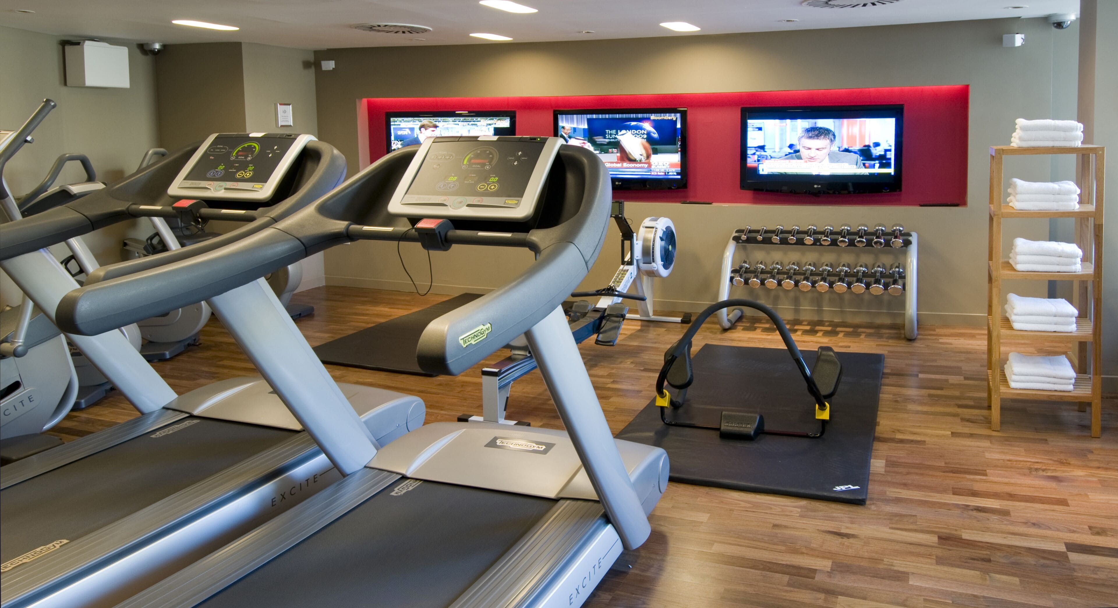 A gym with treadmills, exercise bikes, and a wall-mounted TV.