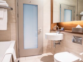 A modern bathroom with a toilet, sink, and mirror.