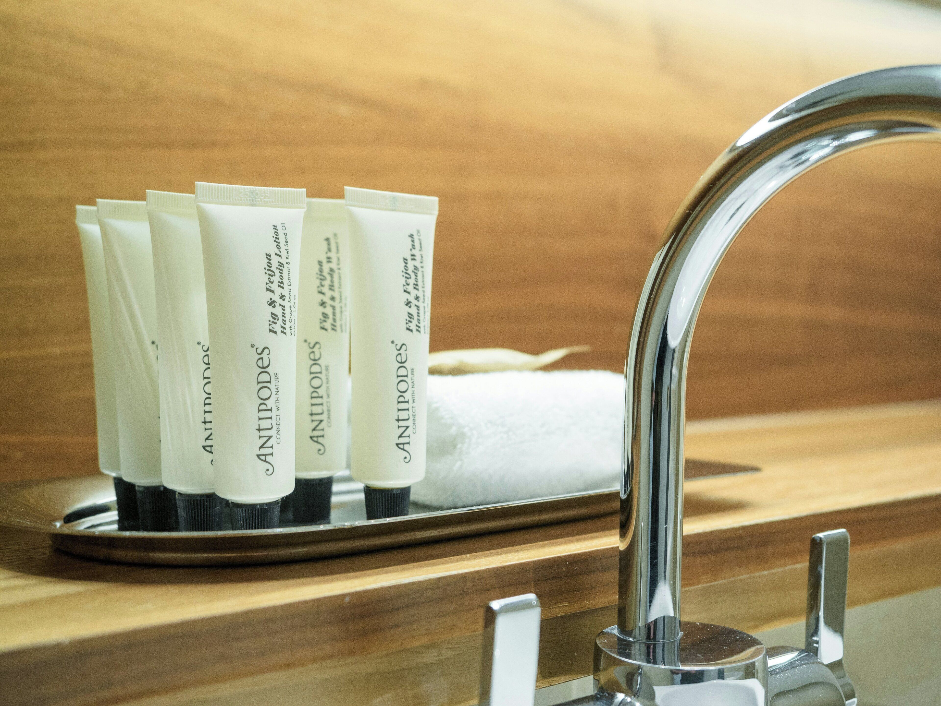 A bathroom sink with a chrome faucet and a tray holding several tubes labeled 'ANTIPODES.'