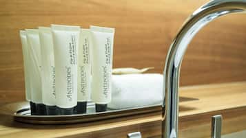 Un lavabo de salle de bain avec un robinet chromé et un plateau contenant plusieurs tubes étiquetés « ANTIPODES ».