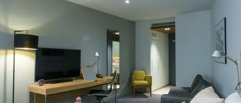 A modern hotel room with a bed, a desk, a TV, a chair, and a wardrobe.