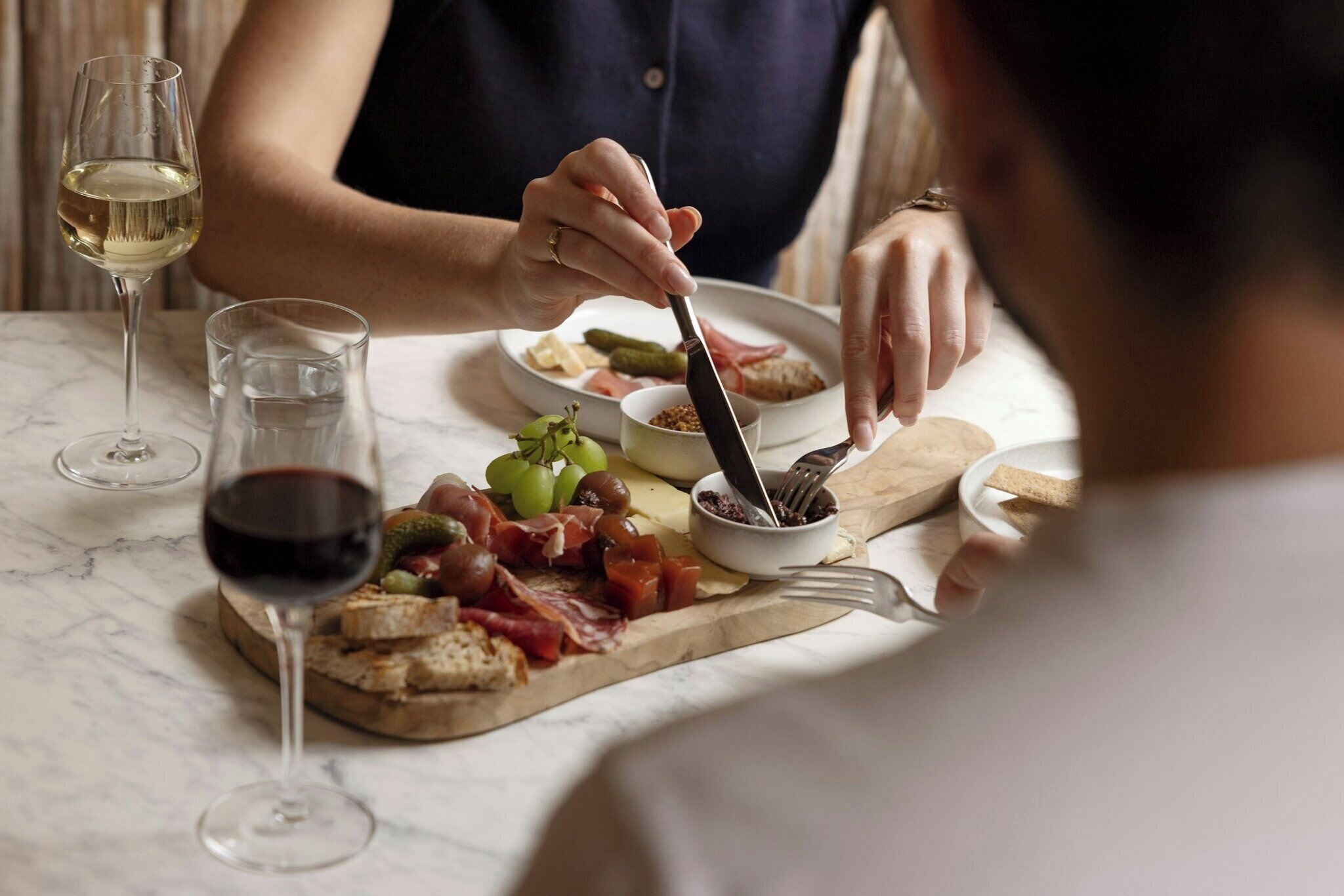 A dining table with a plate of food, a glass of red wine, and a glass of white wine.