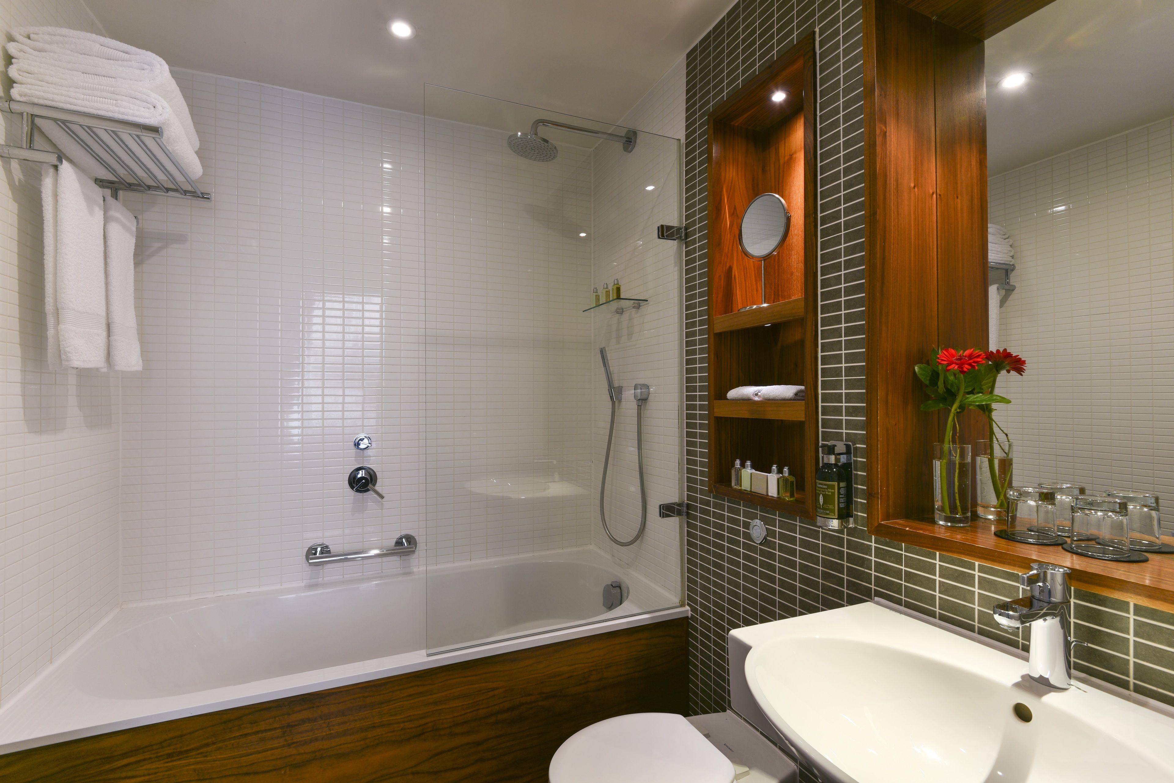 A modern bathroom with a glass-enclosed shower, a white sink, and a wooden vanity.
