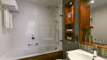 A modern bathroom with a glass-enclosed shower, a white sink, and a wooden vanity.