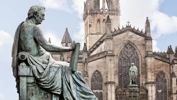 A statue of a seated figure with a building in the background.